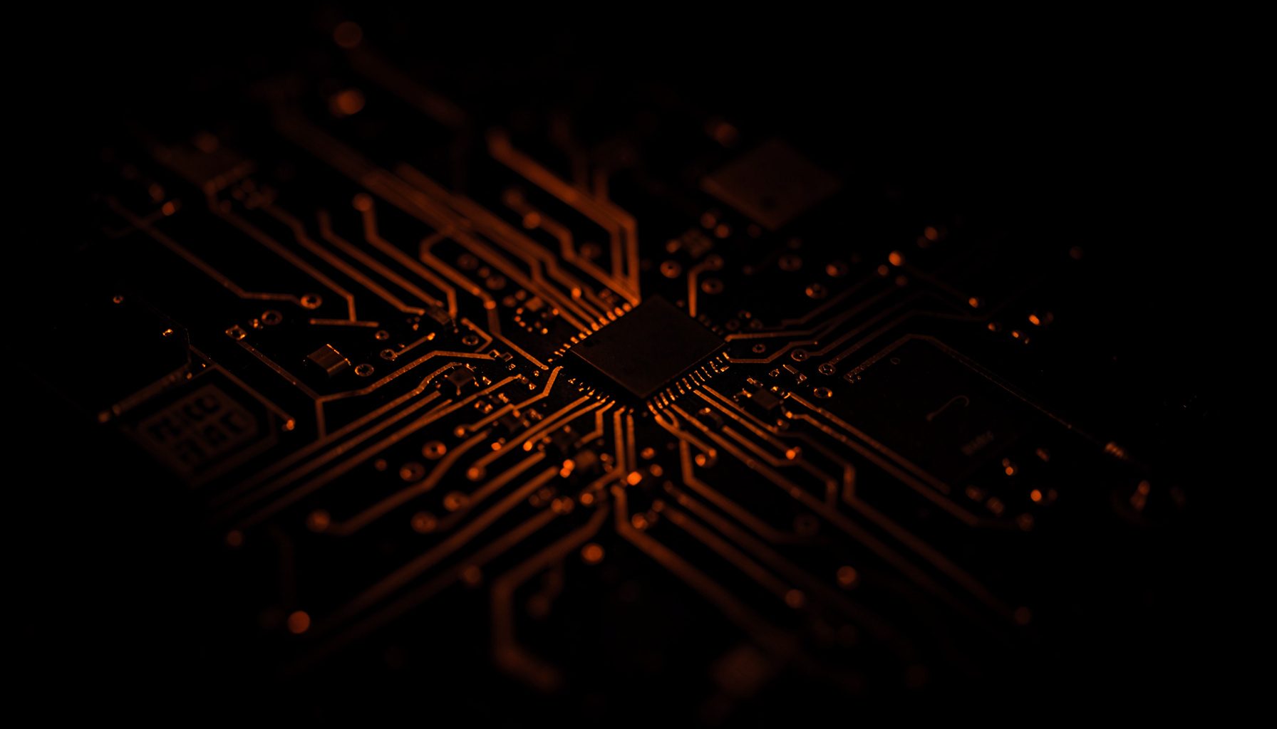 Gros plan sombre d'un circuit imprimé avec des tracés cuivrés et des puces électroniques, éclairé par une faible lumière